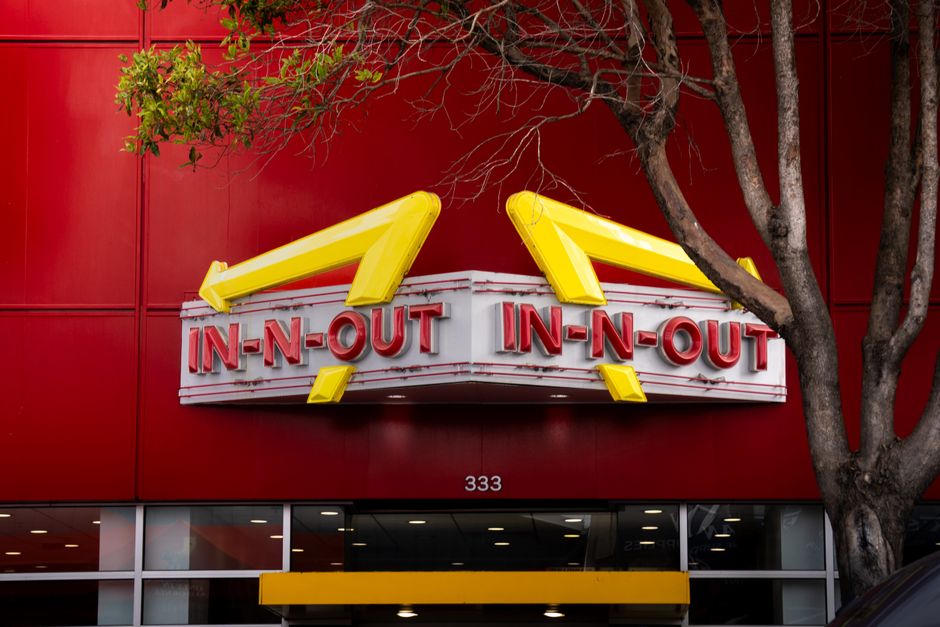 特徴的なIn-N-Outバーガーの看板、鮮やかな赤い背景と前景の木々。