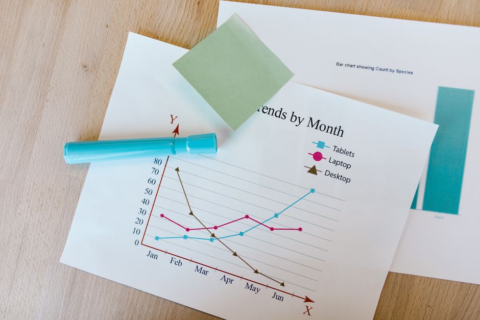 カラフルなグラフ、付箋、マーカーが置かれたデスクで、データ分析テーマに最適です。
